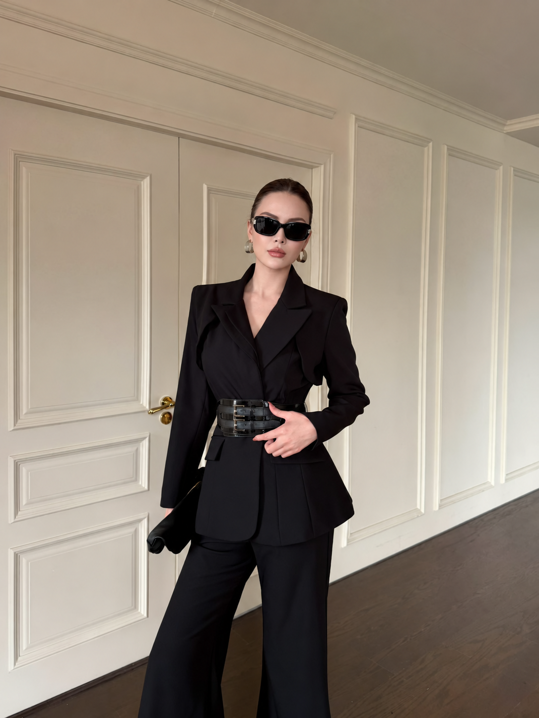 Full-length black tailored blazer and wide-leg trousers with double-buckle belt