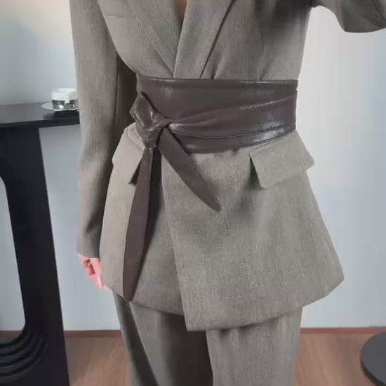 Elegantwom gray tailored blazer and wide-leg pants set video showing a woman wearing the structured grey suit with a contrast brown wrap belt and notched lapel.