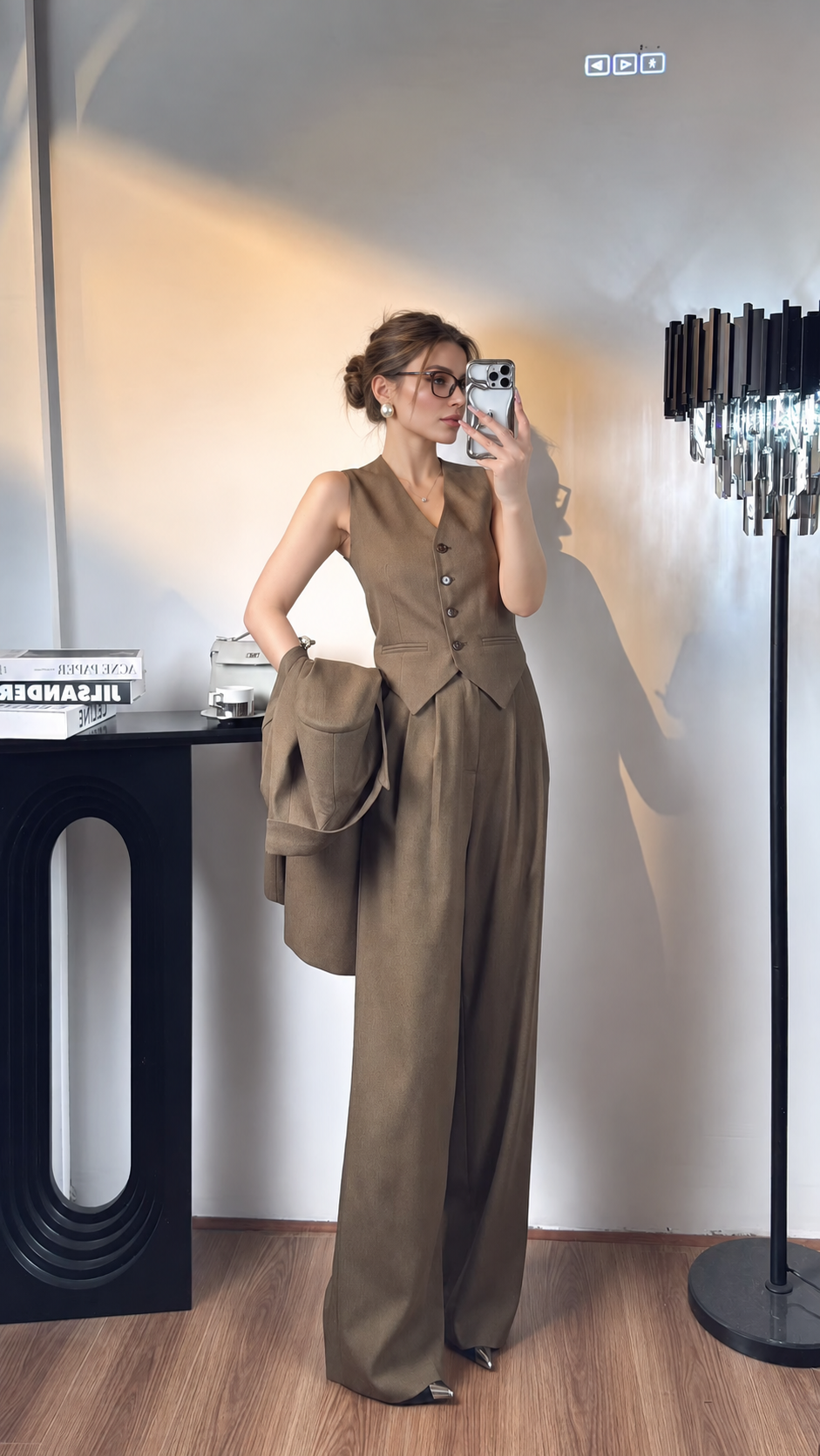 Women's brown button-front vest and wide-leg trousers with matching blazer held at the side