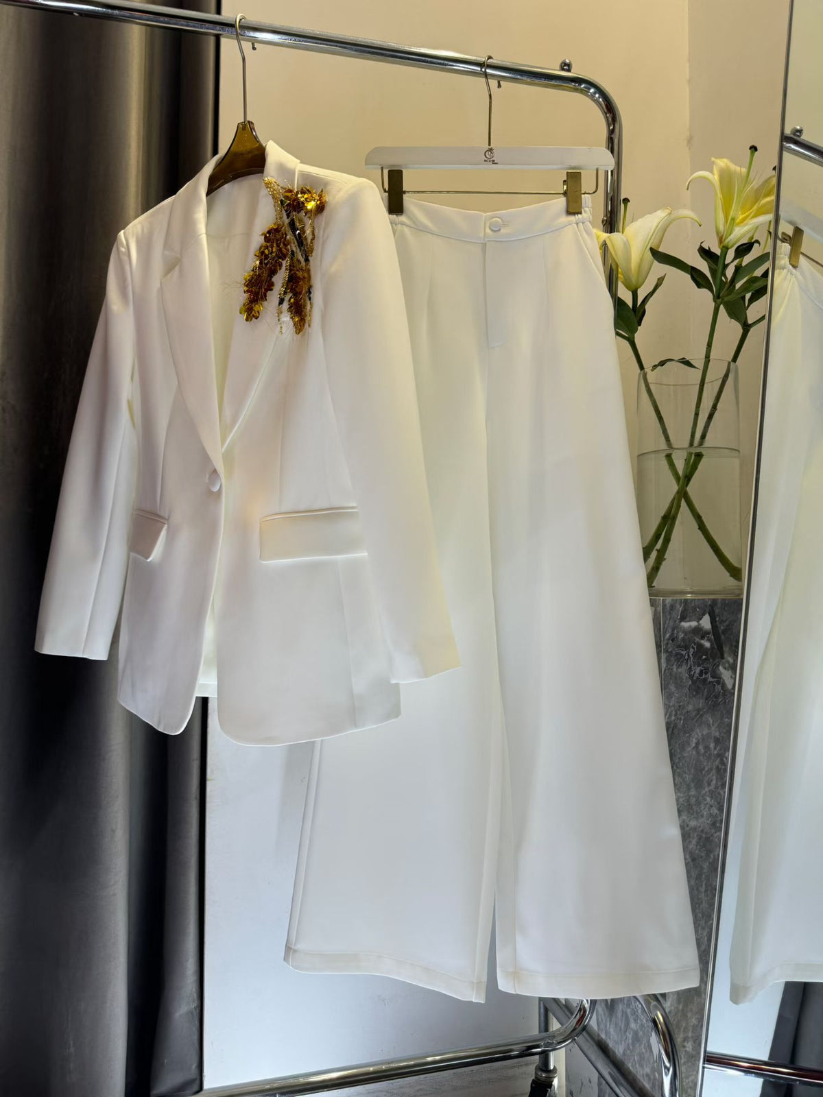 White blazer and wide-leg pants on hangers with gold-tone shoulder appliqué